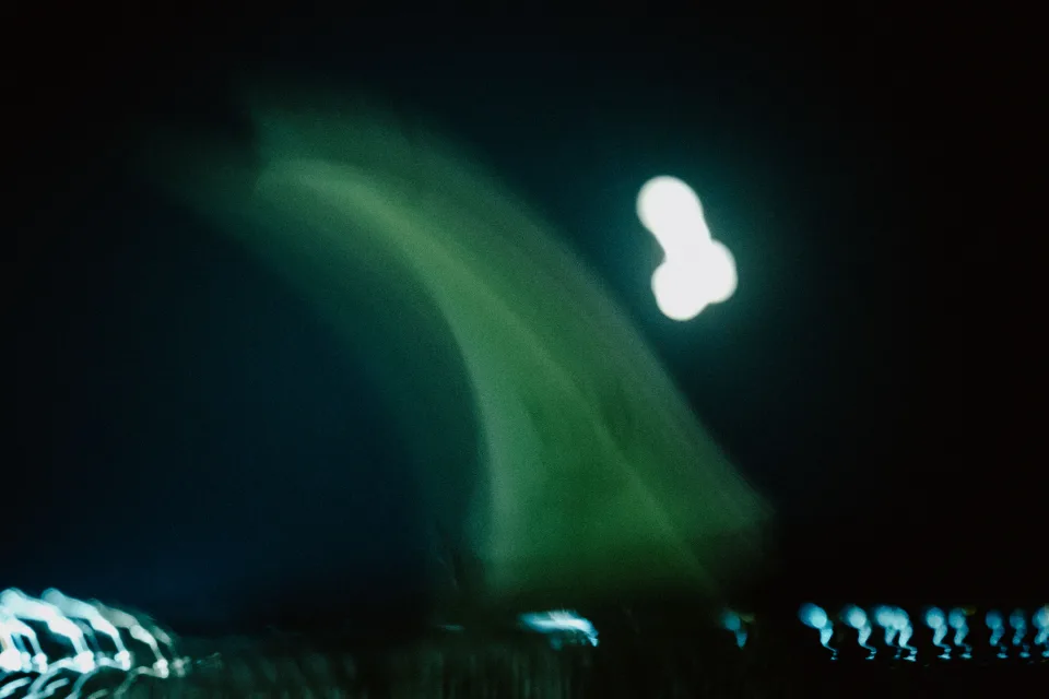 Silhouette floue et lumière verte au bord de l’eau pendant la nuit